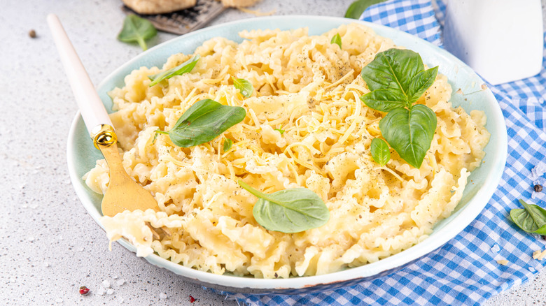 Creamy mafaldine pasta in bowl on gingham towel