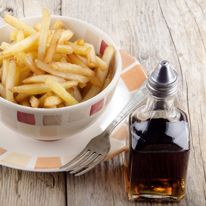 french fries and malt vinegar on a rustic table