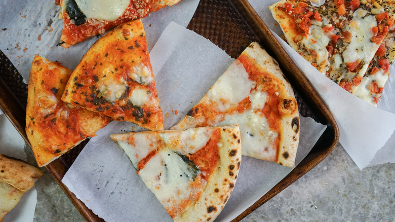 Close up slices of pizza on pan and parchment paper