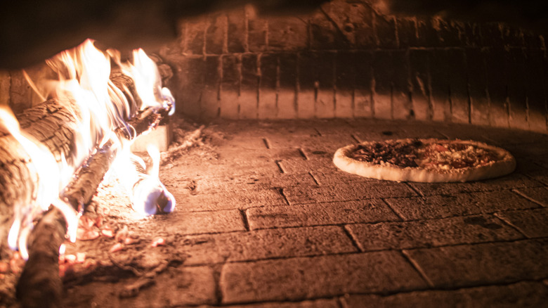 Pizza baking next to wood fire