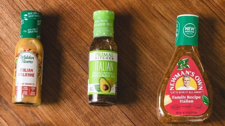 Three salad dressings on brown wooden background