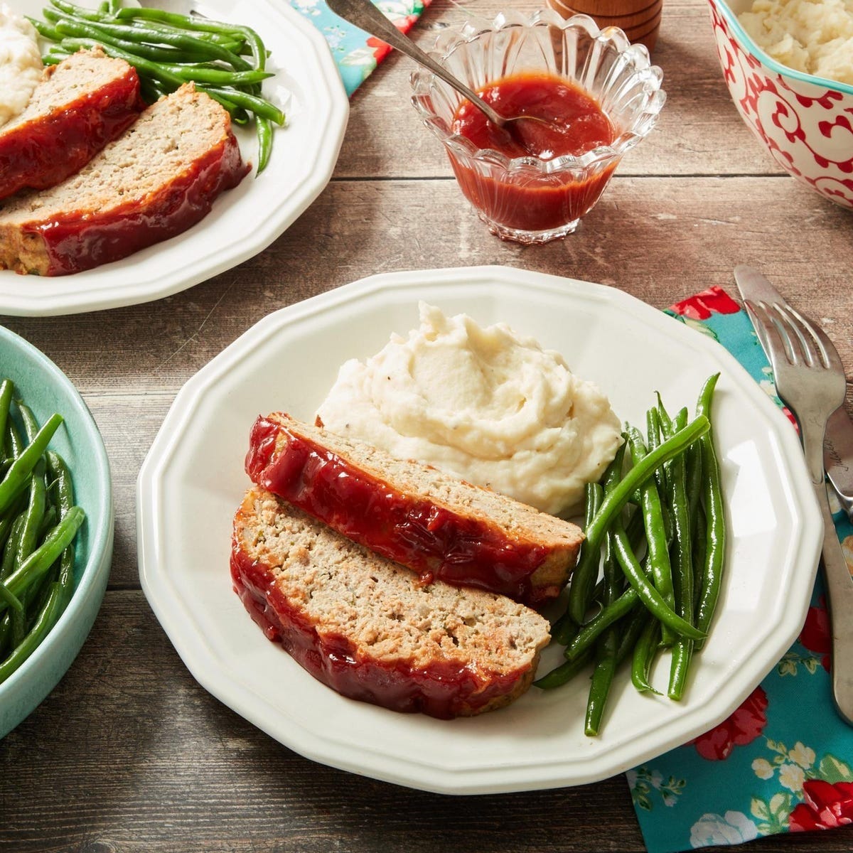 plates of meatloaf served with mashed potatoes and green beans