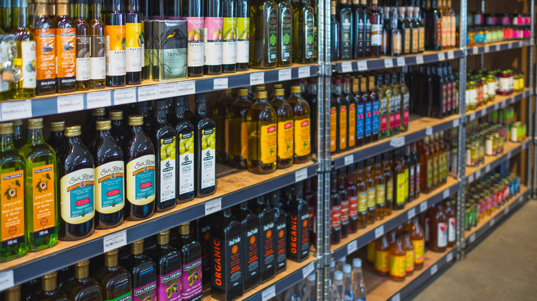 supermarket shelves packed with various olive oil bottles brands