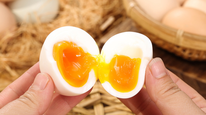 Hands holding a jammy boiled egg