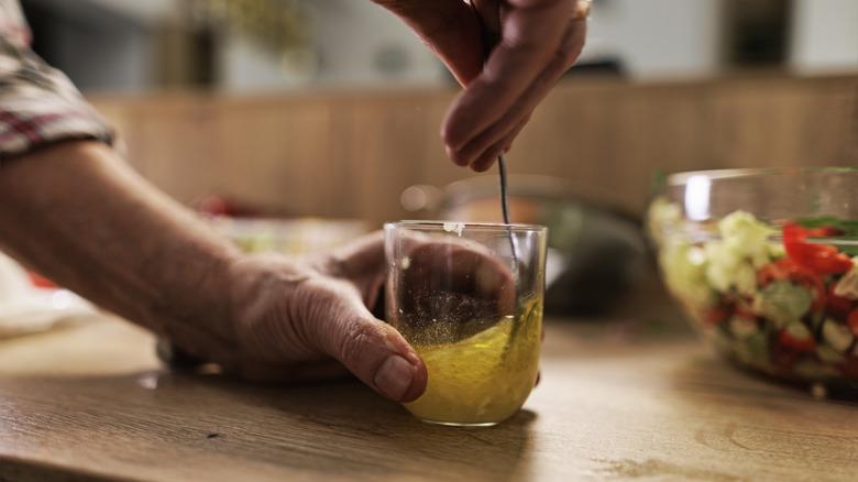Hands stirring vinaigrette in a glass