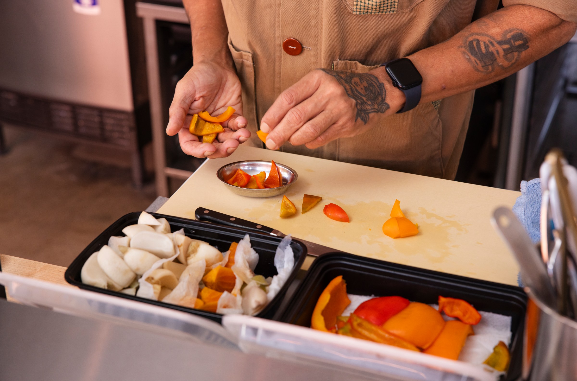 A chef places pieces of pickled bell pepper into a silver bowl at Dream Deli in Portland, Oregon.