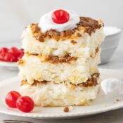 three pineapple angel food cake squares topped with whipped cream and a cherry
