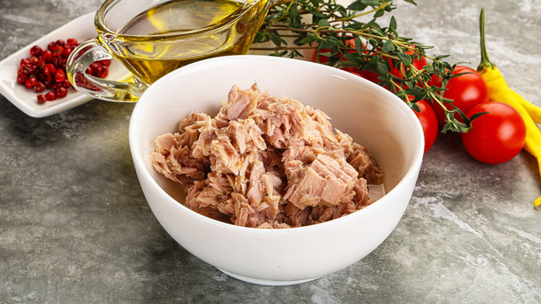 Bowl of tuna next to oil and tomatoes