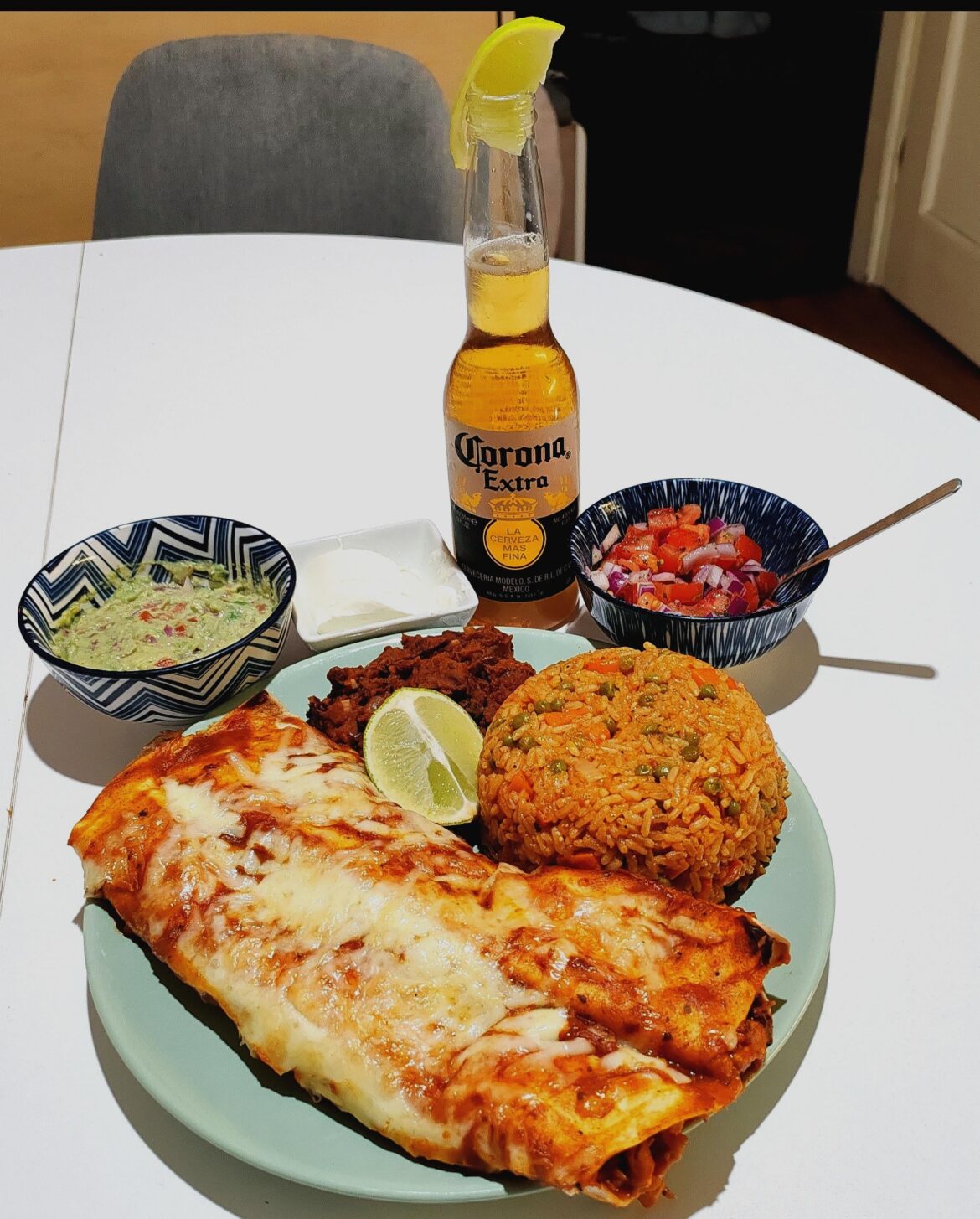 Chicken enchiladas, frijoles refritos, Mexican rice with guac, salsa and sour cream