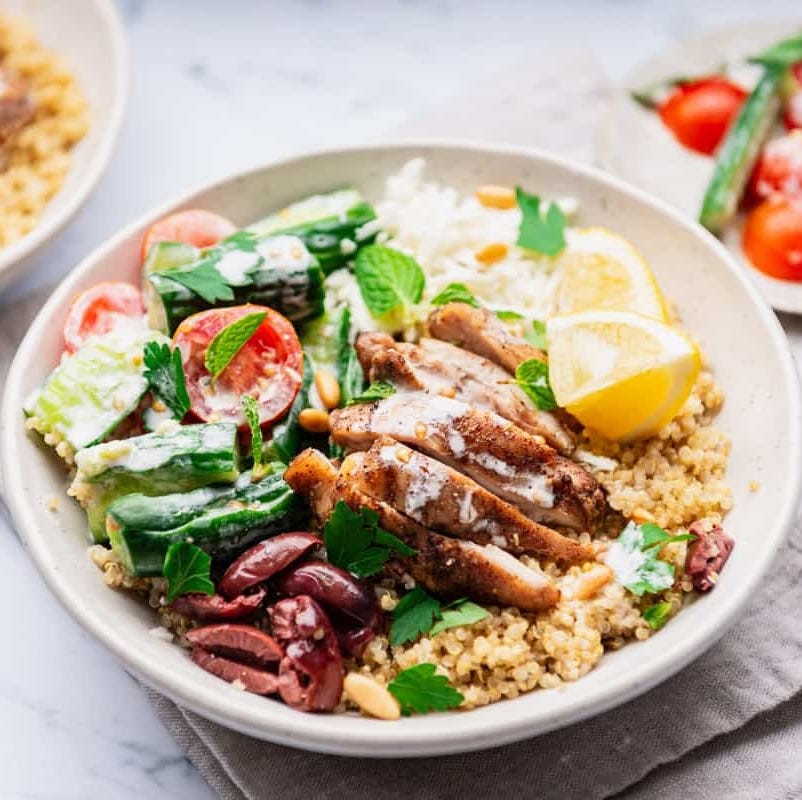 bowl of quinoa salad with grilled chicken vegetables and lemon