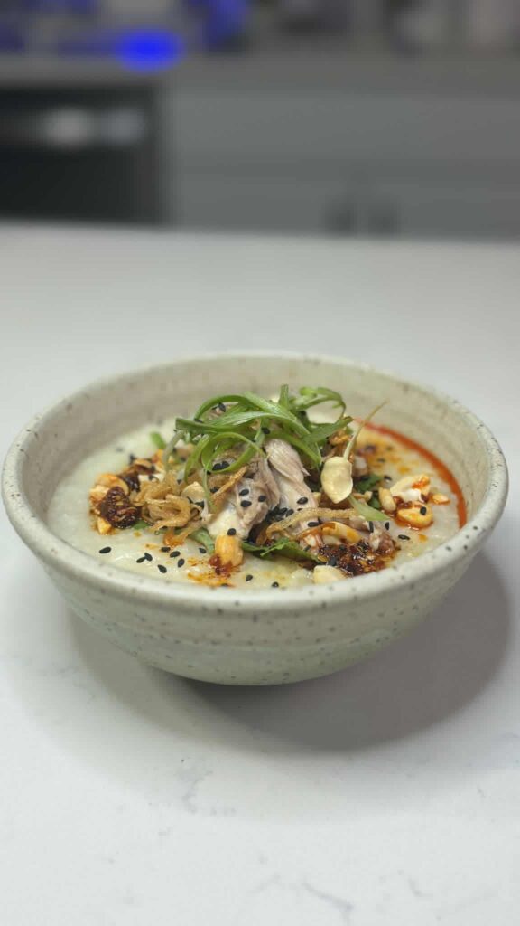 Chicken Congee, Cilantro, Chicken Thighs, Fried Shallots, Roasted Peanuts, Scallions, Chili Oil, Black Sesame Seeds