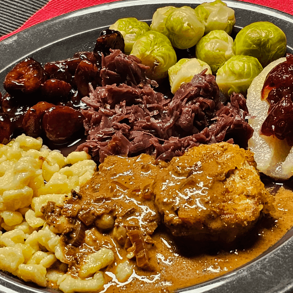 Low-temperature cooked pork fillet medallions with homemade Spätzle in a hearty, creamy white-wine and porcini sauce, served with red cabbage, Brussels sprouts and glazed chestnuts, and to add some more contrast half pears with lingonberry