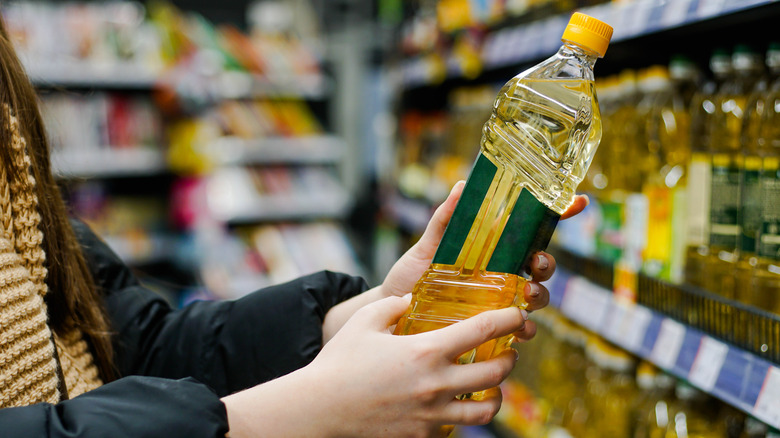A woman inspects the label of a seed oil bottle.