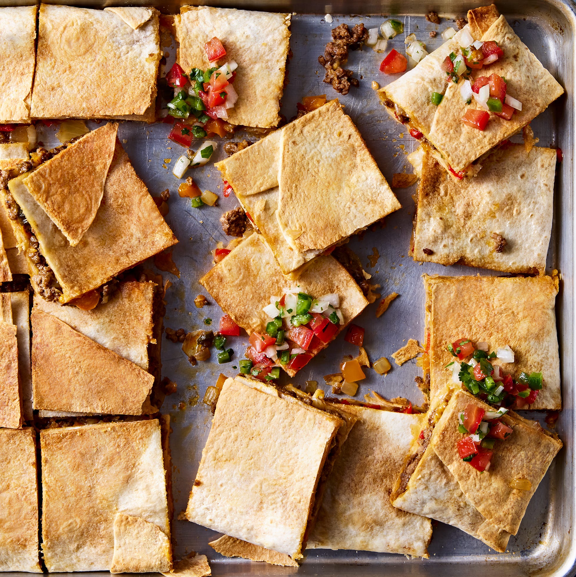tortillas filled with meat and cheese on a sheet pan