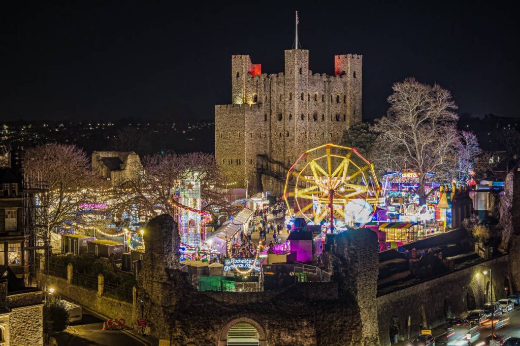 Rochester castle amid Rochester Christmas Markets, including festive shopping stalls, Christmas lights and a ferris wheel