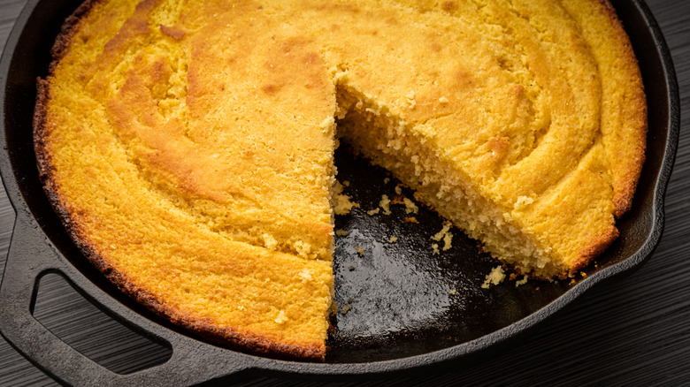 Fresh cornbread right out of the oven baked in a cast iron skillet with a slice removed