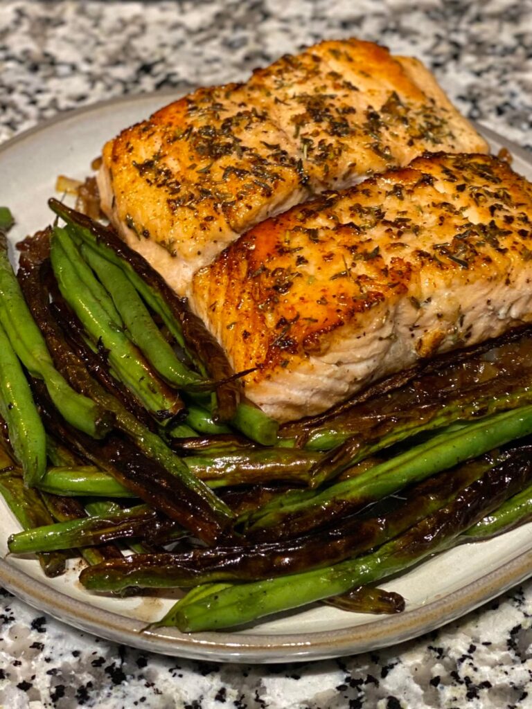 Herb butter salmon over caramelized onions with charred green beans