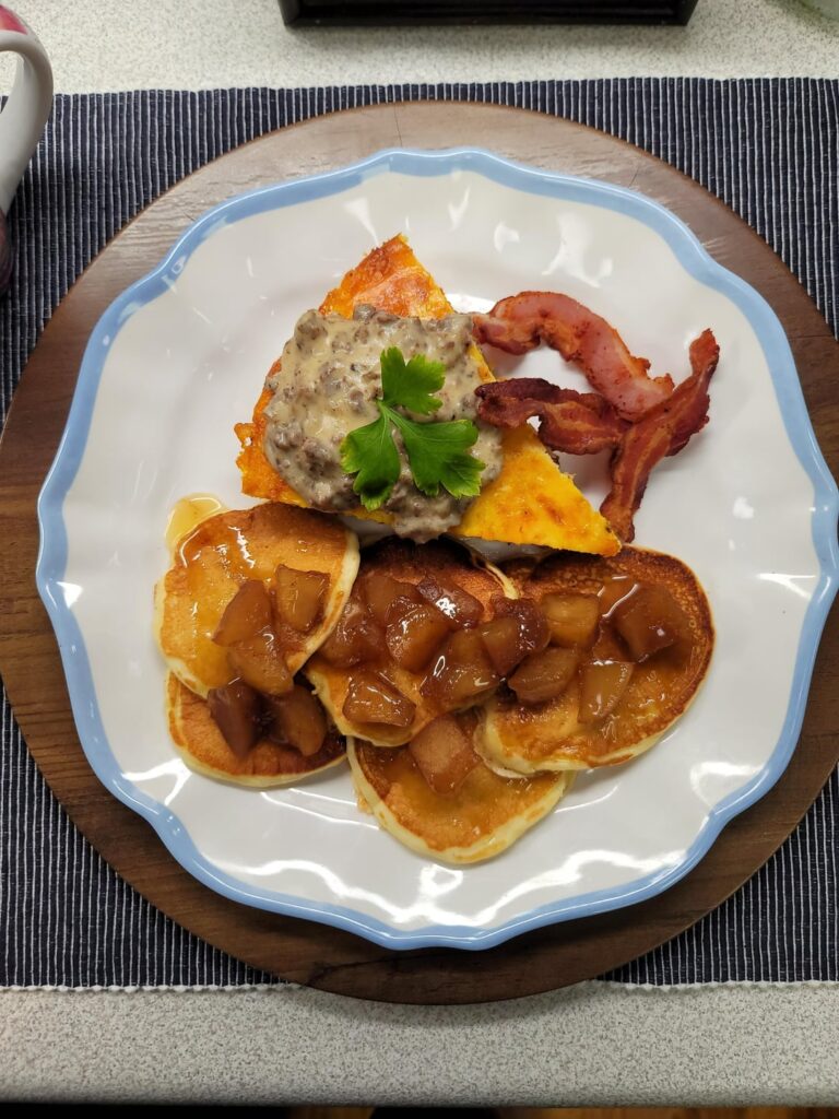 [Homemade]Breakfast! Frittata with venison sausage, onion, red bell pepper, mushroom, smoked gouda, and sharp white cheddar. Topped with sausage gravy. Pancakes with apple compote and a drizzle of orange scented salted caramel. And bacon for show.