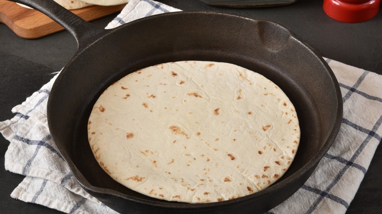 flour tortilla warming in a cast iron skillet