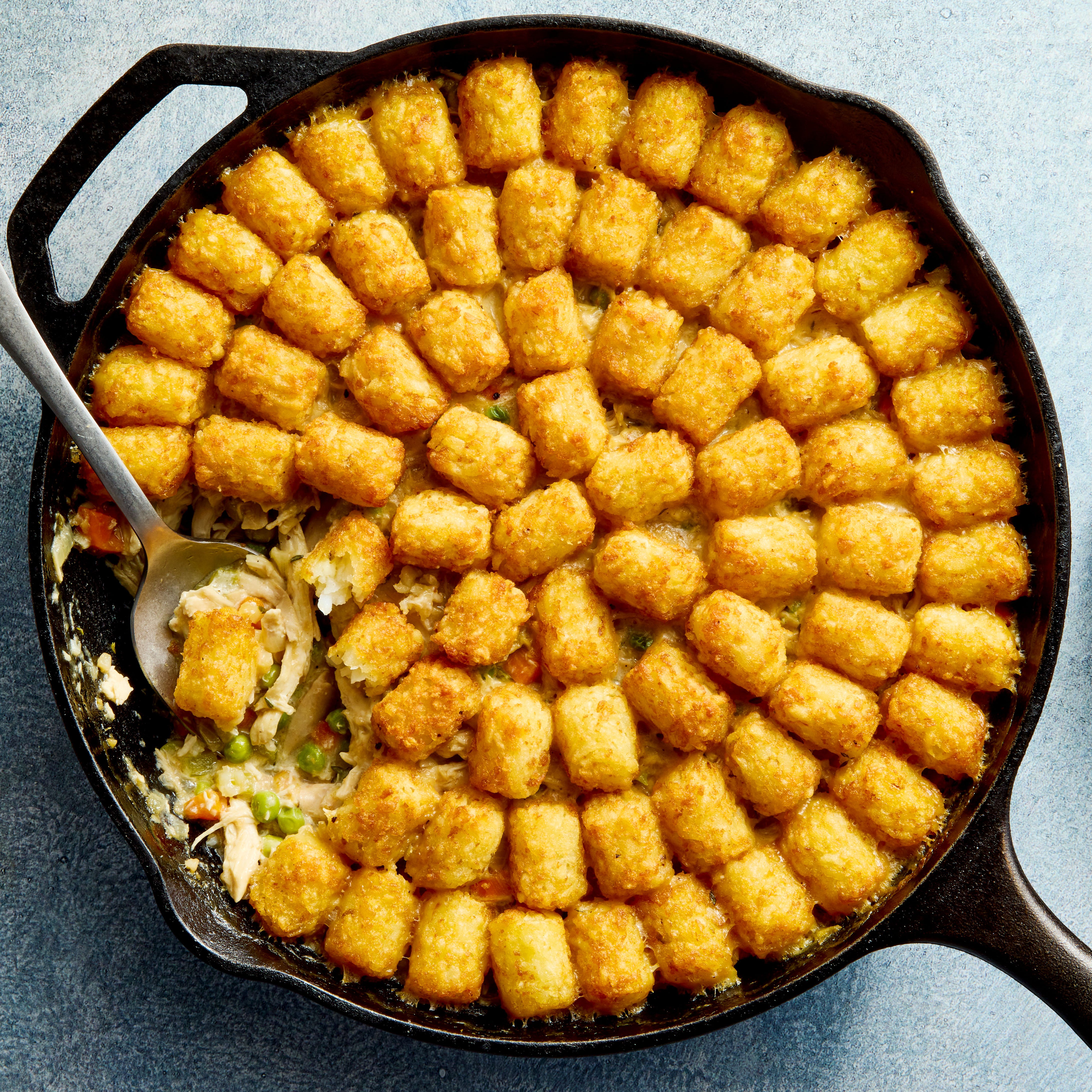 chicken pot pie filling in a skillet topped with tater tots