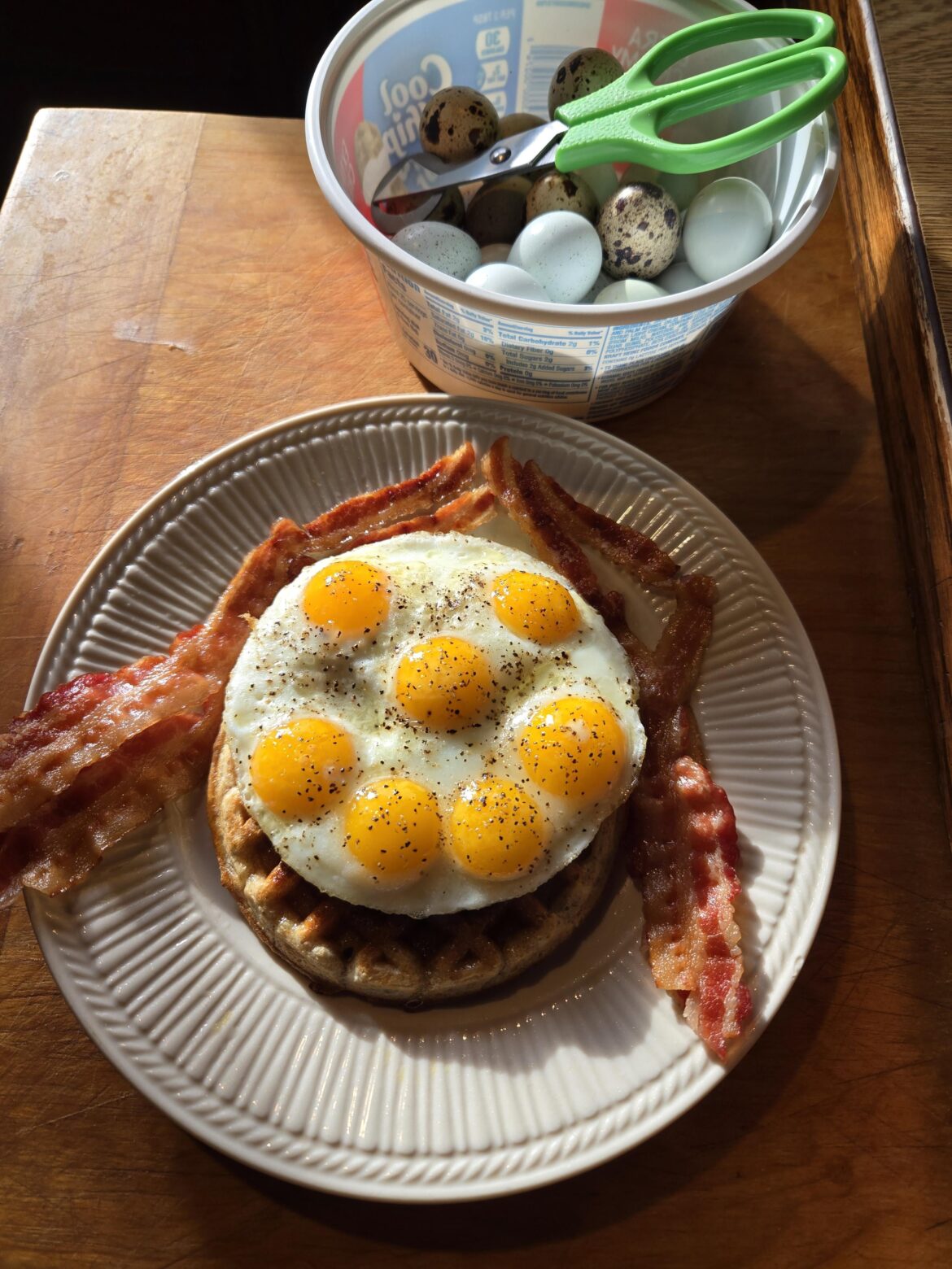 Quail eggs on a waffle with bacon.