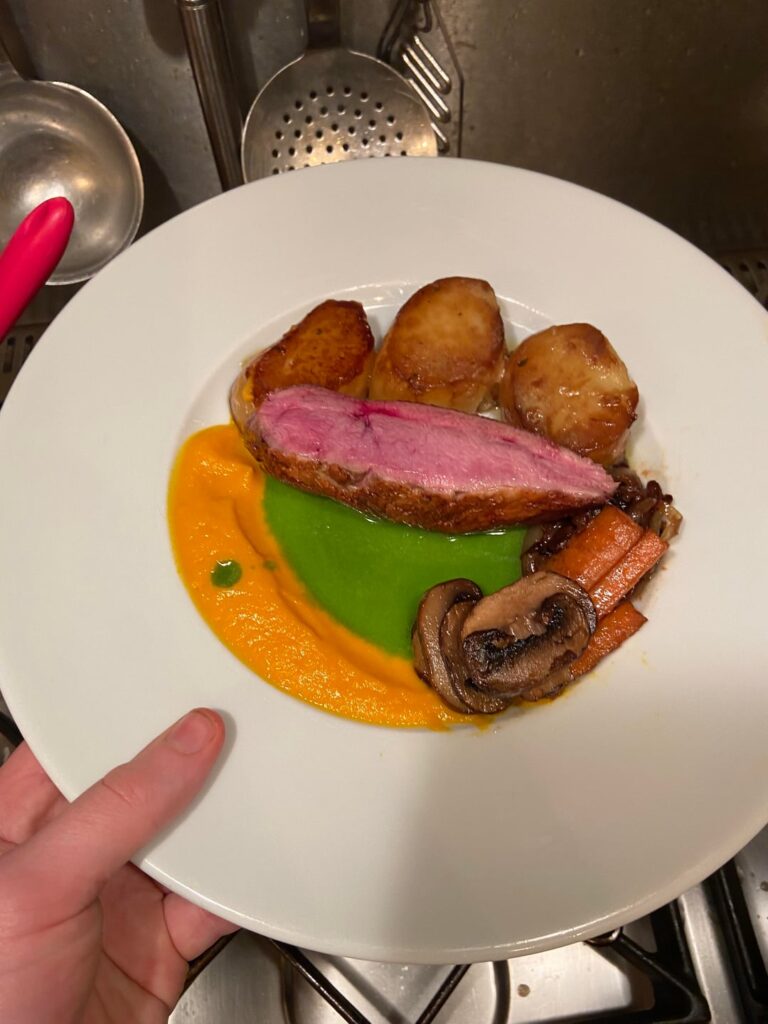 Duck fillet,  pan fried carrots and chestnut mushrooms,  fondant potatoes, carrot purée, sautéed onions and herb oil