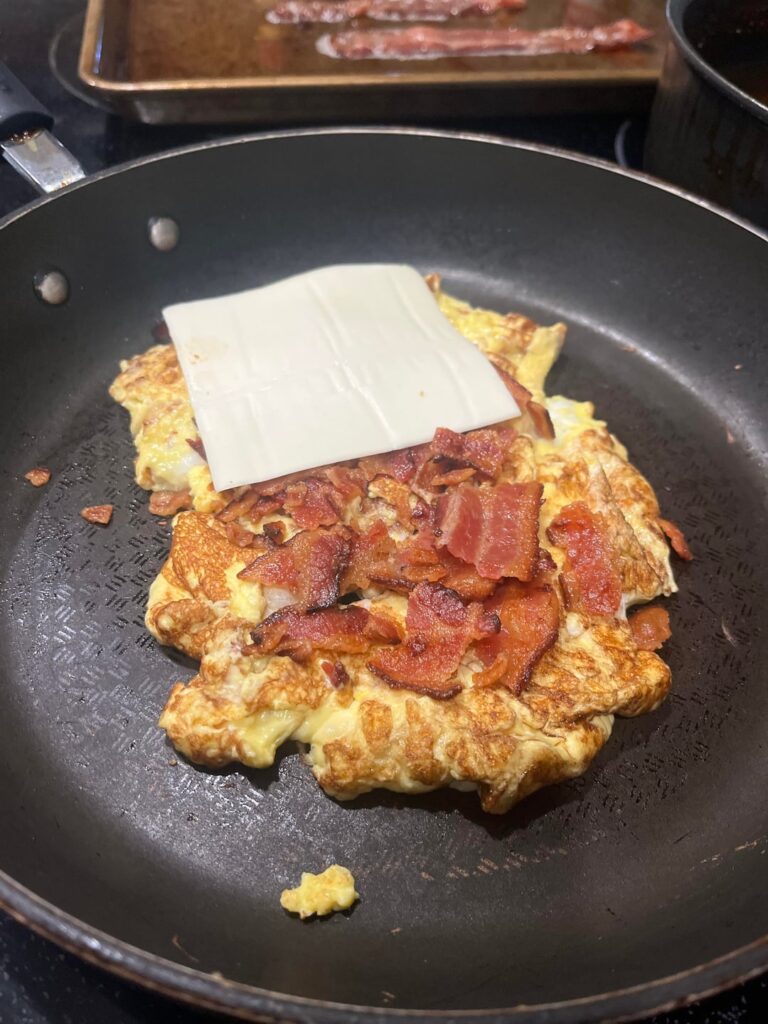 Open faced breakfast sandwich.  Bacon, egg and cheese on a plain bagel.