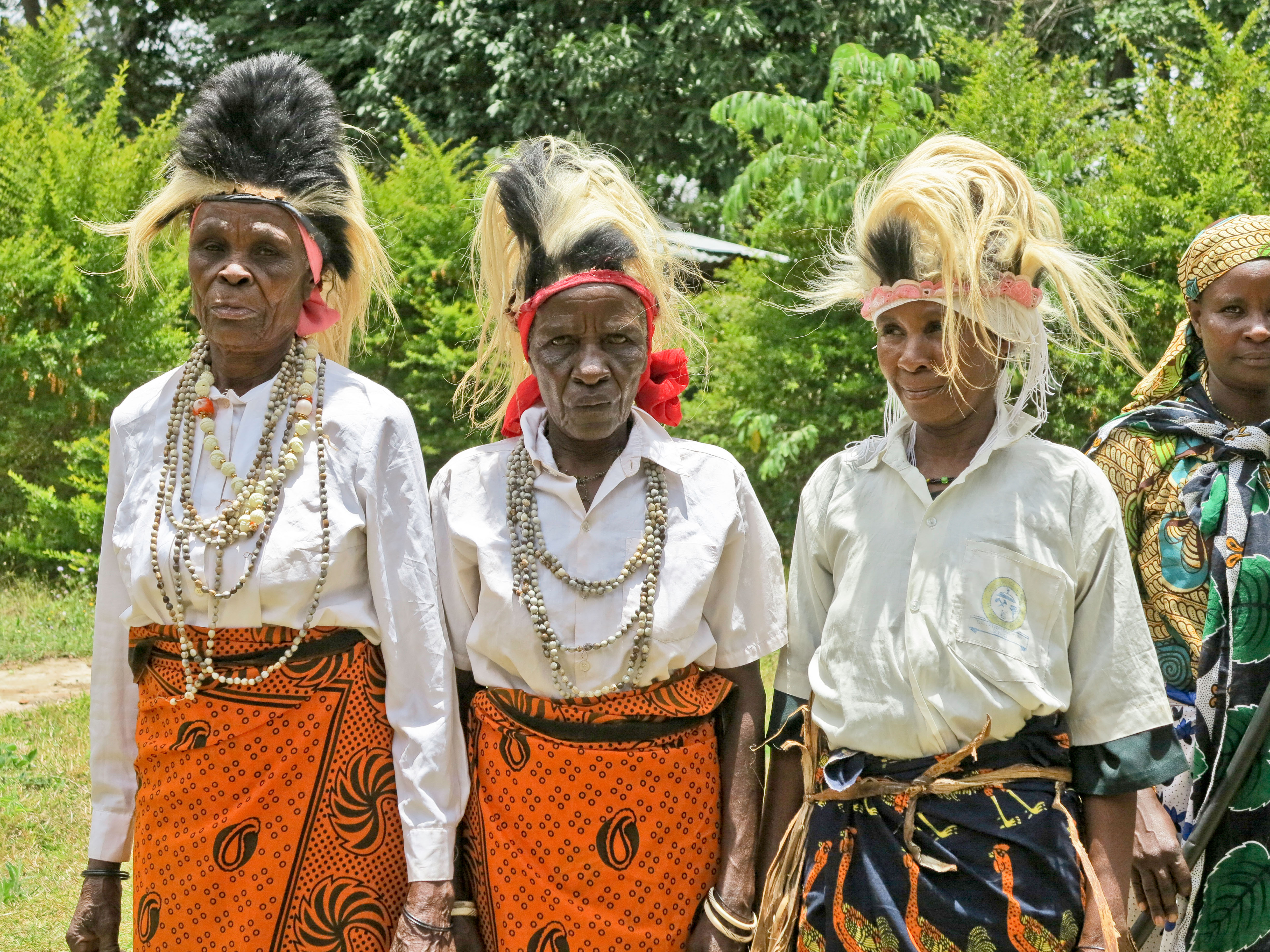 Three Chagga women near Kilimanjaro, Tanzania, wearing traditional clothing and elaborate hairstyles.