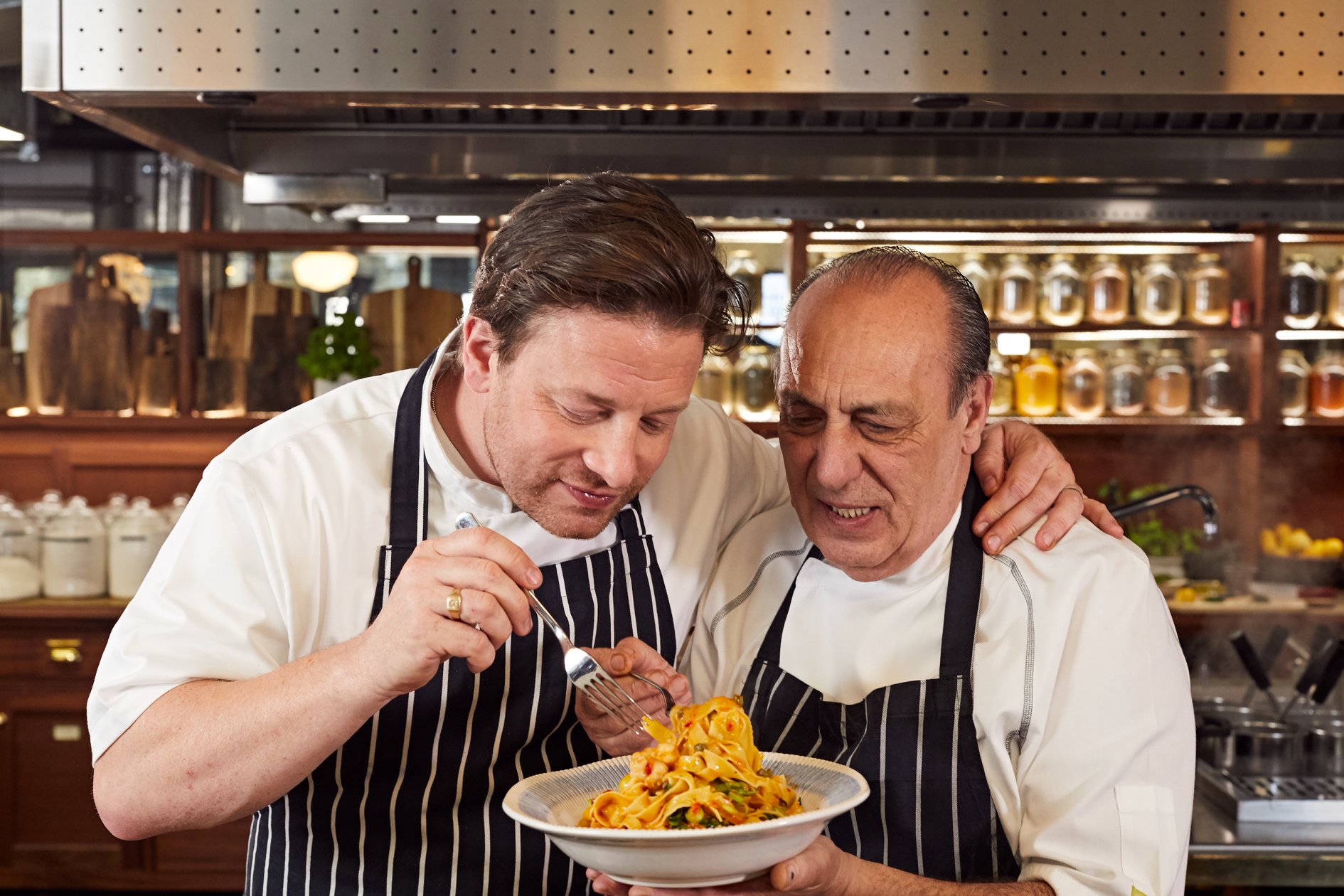 Jamie Oliver and Gennaro Contaldo looking at a plate of pasta.