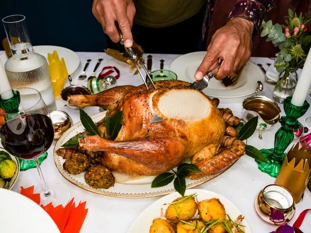 Hands Of Man Carving Roasted Turkey At Traditional Christmas Table