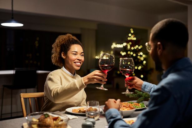Happy young couple toasting red wine while celebrating Christmas