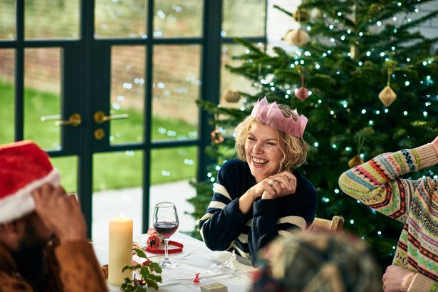 White woman in her 50s sitting at dinner table with family, having relaxed conversation