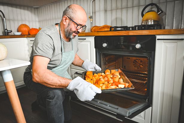 man preparing a festive dinner, baking vegetables in the oven