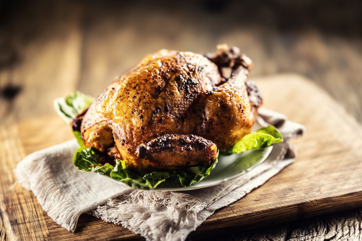 Roasted whole chicken on wooden cutting board.