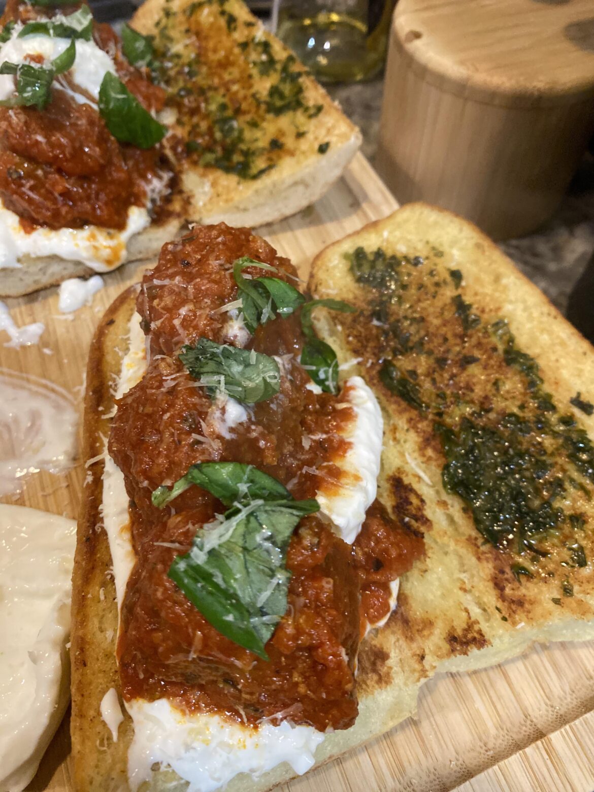 Meatball parm with burrata, on garlic bread with basil pesto