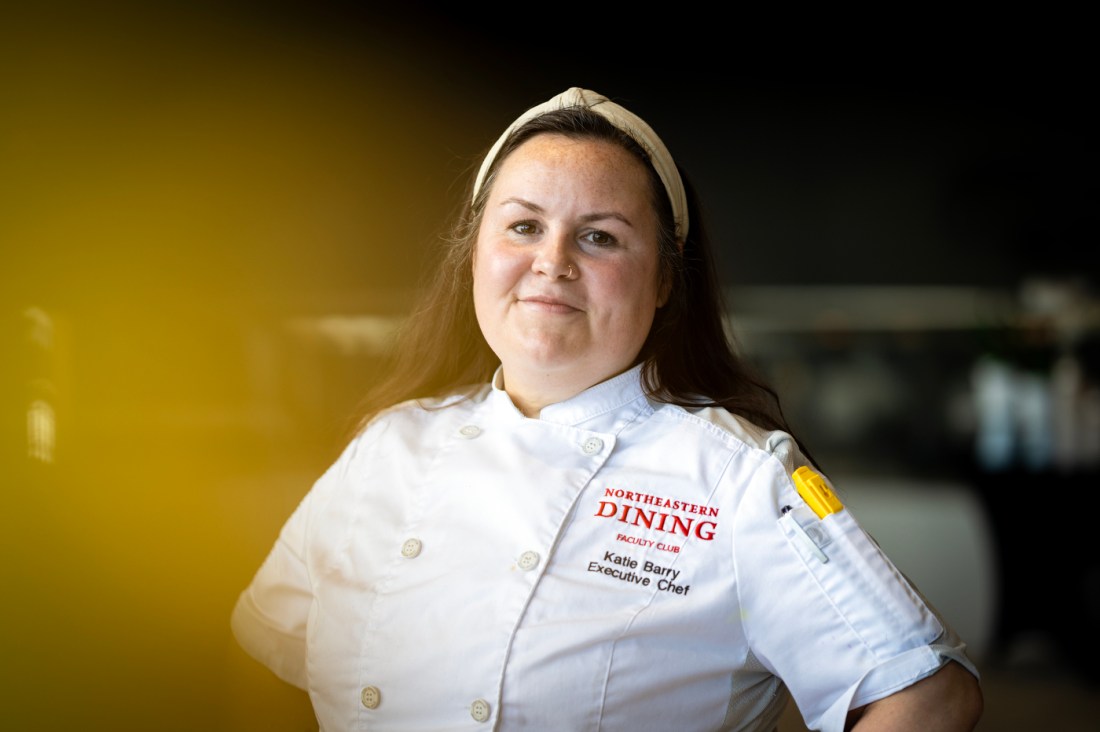 Katie Barry, an executive chef at Northeastern University, stands with her hands on her hips in a white chef's coat.