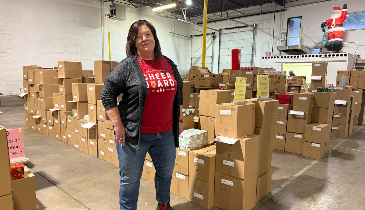 A woman is shown standing in a warehouse, with boxes stacked all around her.