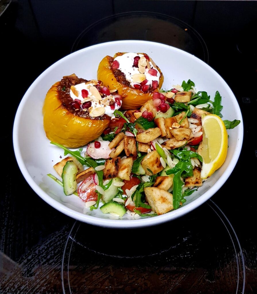 Middle Eastern Inspired Stuffed Peppers with Harissa, and Fattoush Orzo Salad. Finished with Yoghurt, Sumac, Herbs, Almonds and Pomegranate Seeds.