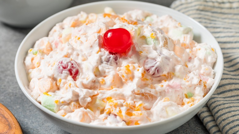 Ambrosia Fruit Salad with Whipped Cream Fruit and Marshmallows in a white bowl on grey table