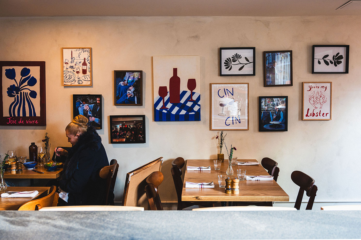 Pictures hang on a wall inside a dining room.