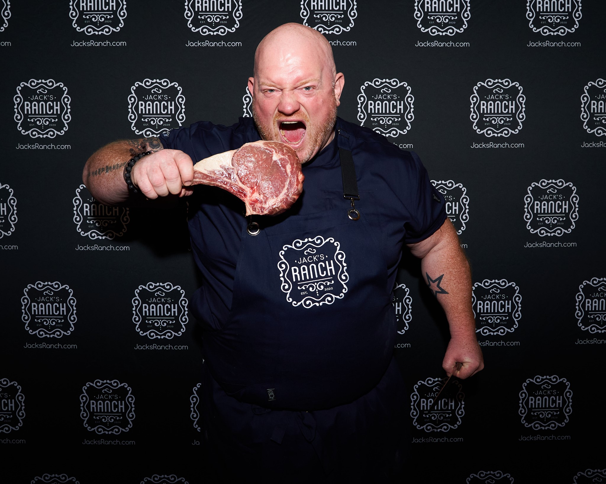 A photo of Declan Hogan, Jack Ranch’s chef biting into a big steak.