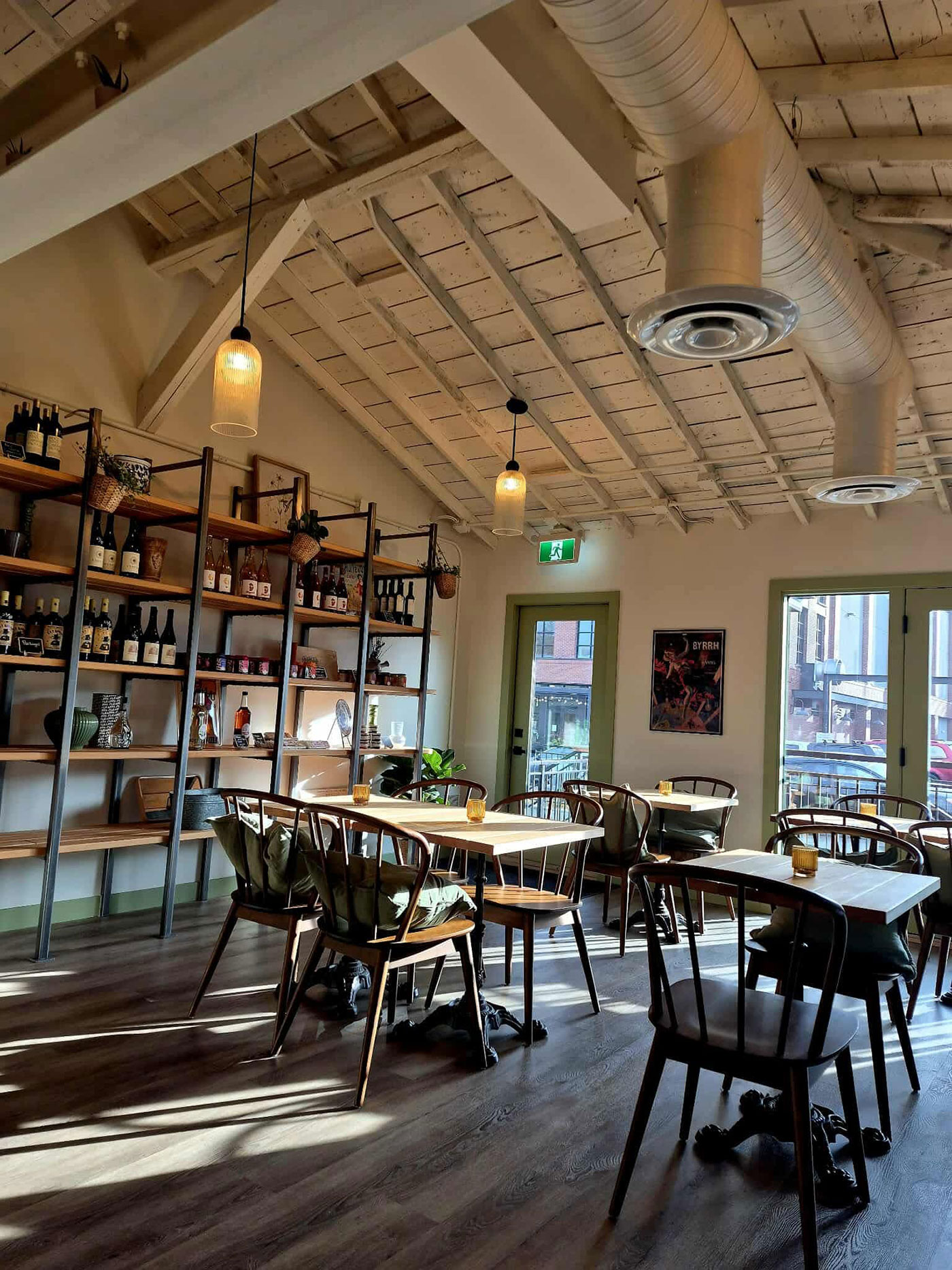 A room with wine on shelves and tables with chairs