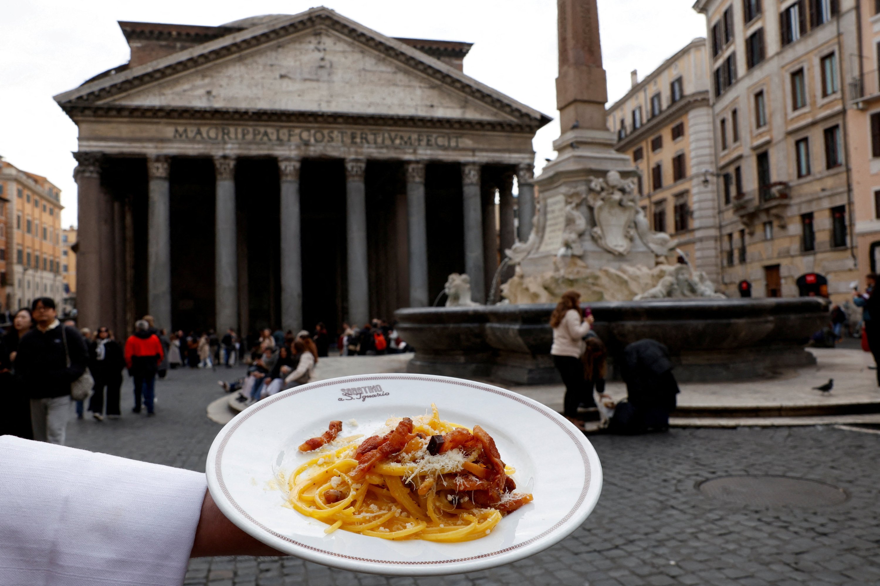 A waiter shows a plate of traditional pasta Carbonara in front of the Pantheon as Italian cuisine awaits a crucial UNESCO decision that could recognise it as an Intangible Cultural Heritage of Humanity in this illustration picture taken in Rome, Italy, Dec. 3, 2025. (Reuters Photo)