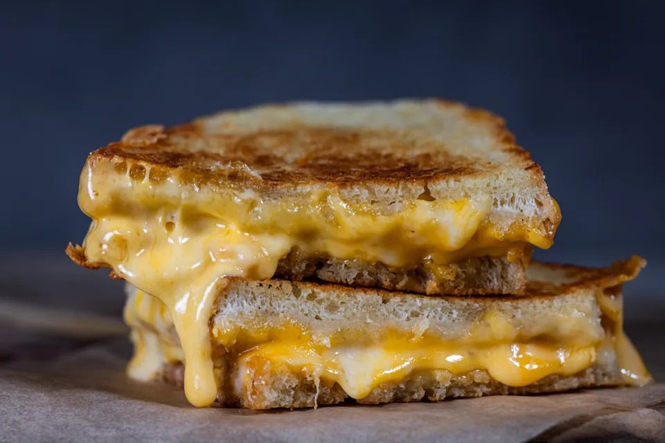 A stacked grilled cheese sandwich with melted cheese oozing from between the slices of toasted bread
