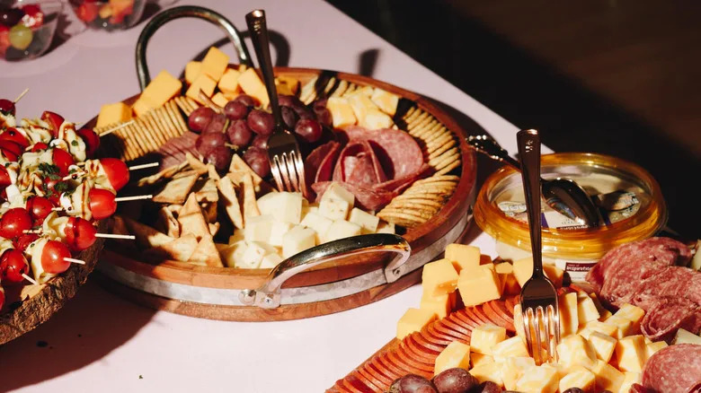 Cheese, crackers, and meat arranged on wooden serving trays on a table