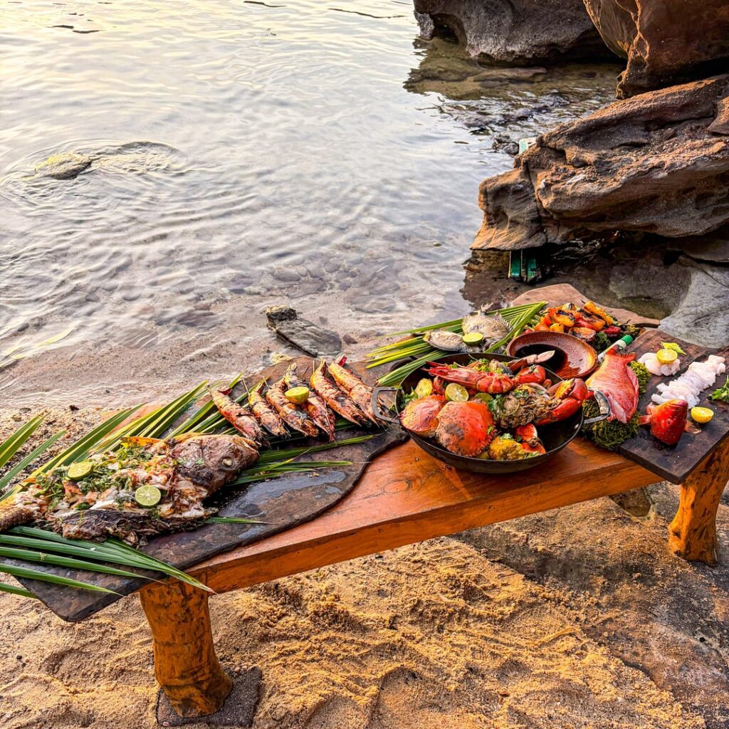A seafood feast at sunset before New Year. Mangrove snapper grilled with chilli sauce, giant prawns with Thai hot paste, Cajun mudcrab pot with baked potato and corn, sashimi coral trout and roasted vegetables.