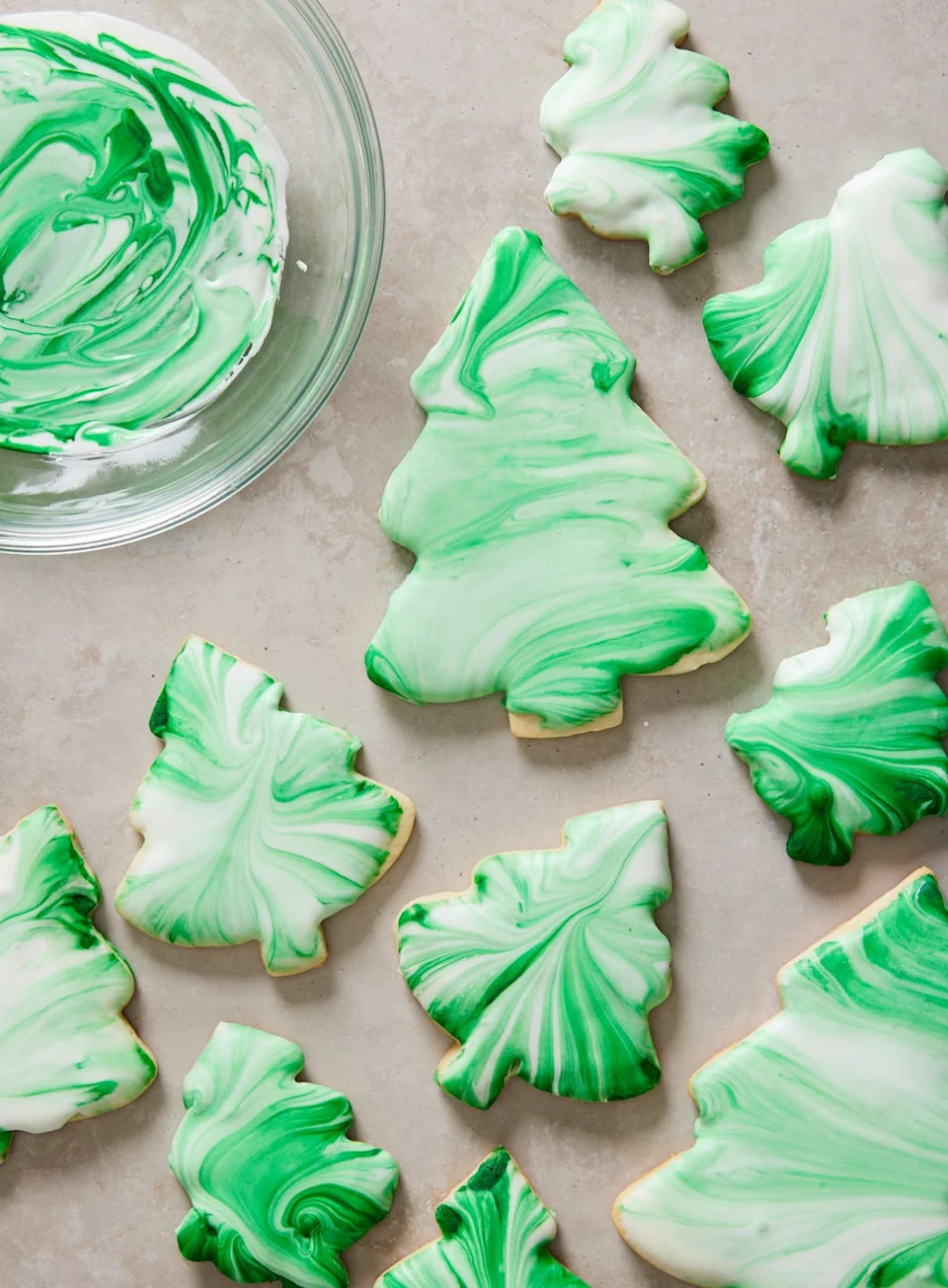 christmas tree cookies decorated with tie dye style green and white swirl icing