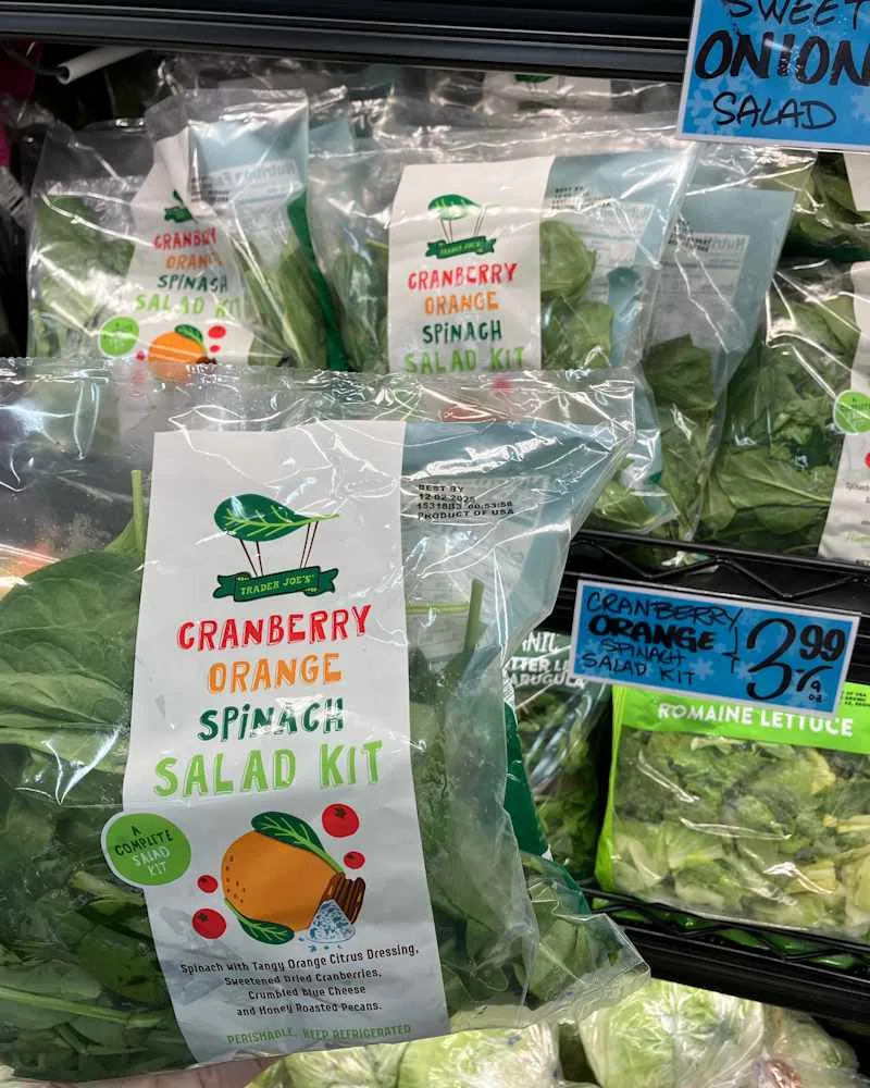 Someone holding a package of Trader Joe's Cranberry, Spinach and Orange salad mix.