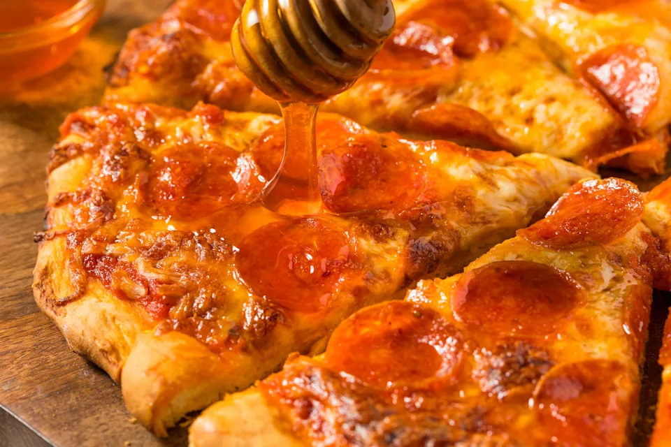Pepperoni pizza slices being drizzled with hot honey