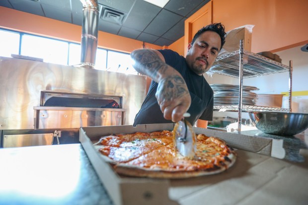 Milan Coal Fired Pizza & Grill co-owner Jorge Fuentes prepares a pizza on Thursday, Dec. 18, 2025. (JASON ARDAN / STAFF PHOTOGRAPHER)